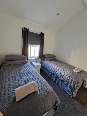 a bedroom with two beds and a window at 5 Laurel Court in Ulverston