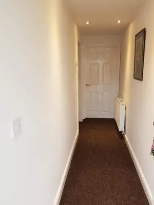 an empty hallway with a white door and a room at 5 Laurel Court in Ulverston
