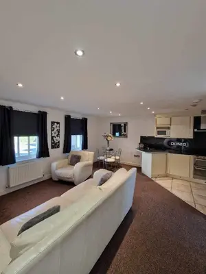 a living room with a white couch and a kitchen at 5 Laurel Court in Ulverston