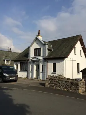 a white house with a car parked in front of it at Wyndcliffe in Grange Over Sands