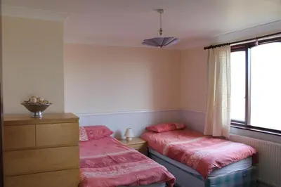 a bedroom with two beds and a dresser and a window at Wyndcliffe in Grange Over Sands