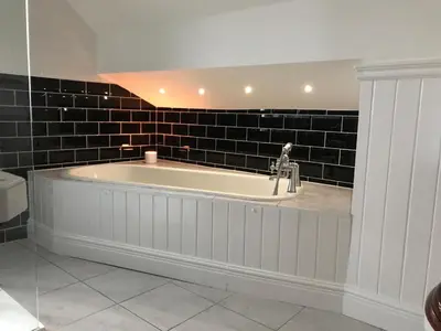 a bath tub in a bathroom with a black tile wall at Wyndcliffe in Grange Over Sands