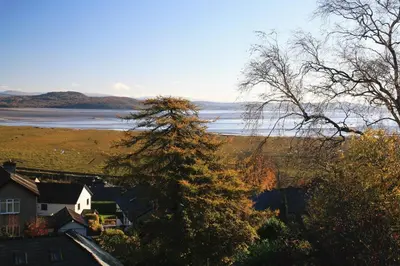 a view of a lake with a house and trees at Wyndcliffe in Grange Over Sands