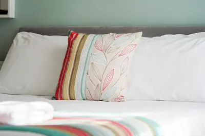 a bed with white pillows and a colorful pillow at The Georgian Hollies Hotel in Blackpool