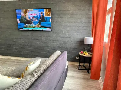 a living room with a couch and a tv on a wall at Kennedy House by Blackpool Service Apartments in Blackpool