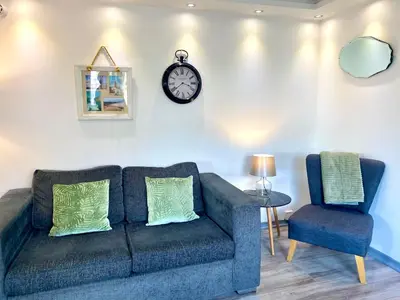a living room with a couch and a clock on the wall at Kennedy House by Blackpool Service Apartments in Blackpool
