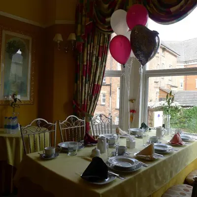 a table with plates and balloons on top of it at Bay Tree House Southport, United Kingdom in Southport