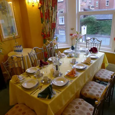 a dining table with a yellow table cloth and plates and chairs at Bay Tree House Southport, United Kingdom in Southport