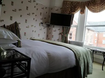 a bedroom with a bed with a tv on the wall at Bay Tree House Southport, United Kingdom in Southport