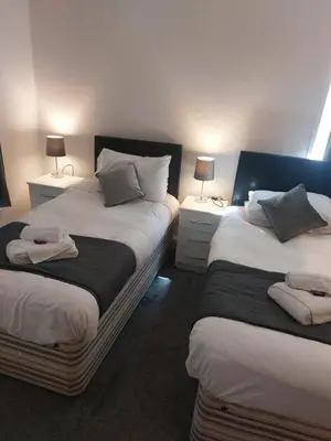 two beds in a room with two lamps on tables at The Sanderling in Morecambe