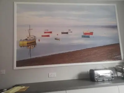 a painting of boats in the water on a wall at The Sanderling in Morecambe