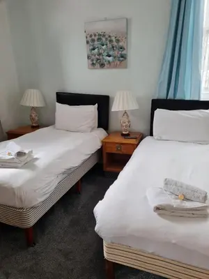 two beds in a room with two lamps on tables at The Sanderling in Morecambe