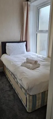 a bed with two towels on it with a window at The Sanderling in Morecambe