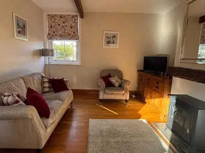 a living room with a couch and a television at Stable Cottage Lytham in Lytham St Annes