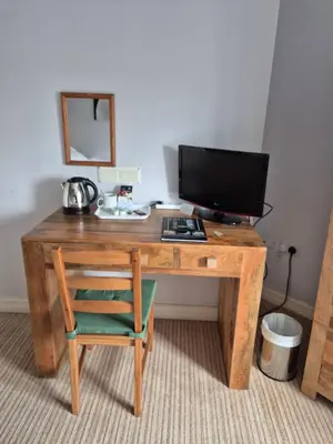 a wooden desk with a computer monitor and a chair at The Port House in Heysham