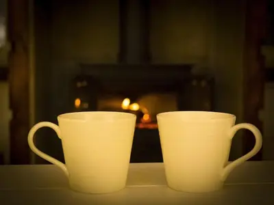 two white cups sitting on a table in front of a fireplace at Castle View in Lancaster