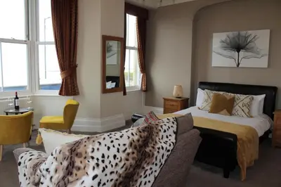 a bedroom with a bed and a couch and windows at The Crown Hotel in Morecambe