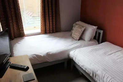 a bedroom with two beds and a desk and a window at The Crown Hotel in Morecambe