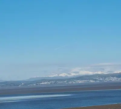 a large body of water with snow covered mountains in the background at The Gateway at Hest Bank in Lancaster