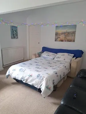 a bedroom with a bed with a white comforter at The Coach House Apartment in Lytham St Annes