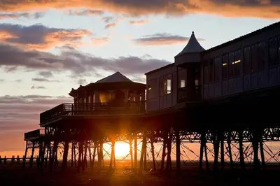 a pier with the sun setting behind it at The Coach House Apartment in Lytham St Annes