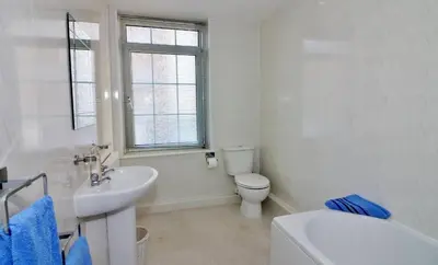 a white bathroom with a toilet and a sink at The Coach House Apartment in Lytham St Annes