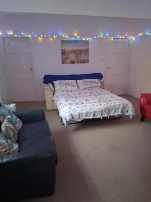 a bedroom with a bed and a couch and lights at The Coach House Apartment in Lytham St Annes