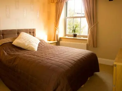 a bedroom with a bed with a pillow on it at Briarcliffe Cottage in Lindale