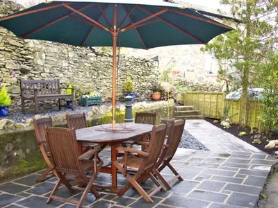 a wooden table with chairs and an umbrella on a patio at Briarcliffe Cottage in Lindale