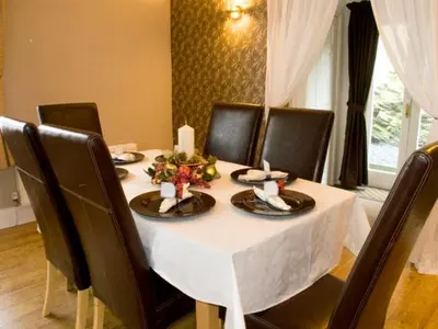 a dining table with black chairs and a white table cloth at Briarcliffe Cottage in Lindale