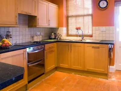 a kitchen with wooden cabinets and a stove top oven at Briarcliffe Cottage in Lindale