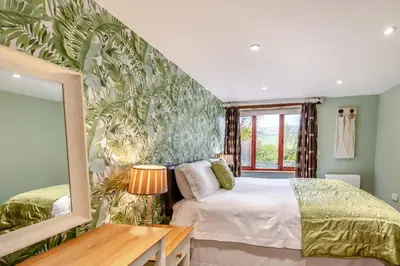 a bedroom with a bed and a green wall at Hill Side Barn in Ireleth