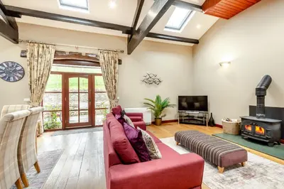a living room with a red couch and a fireplace at Hill Side Barn in Ireleth