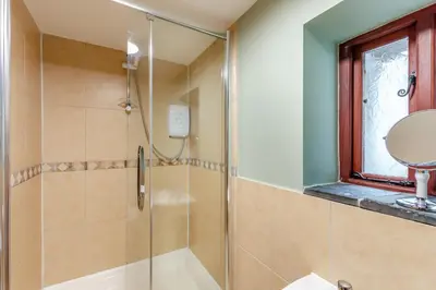 a bathroom with a shower with a sink and a mirror at Hill Side Barn in Ireleth