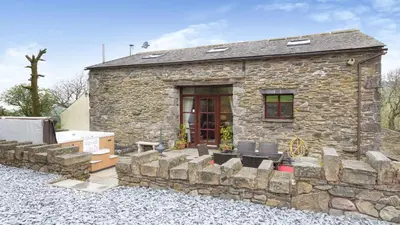 a stone house with a stone wall at Hill Side Barn in Ireleth
