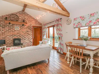 a living room with a couch and a table at Maltkiln Cottage At Crook Hall Farm in Mawdesley