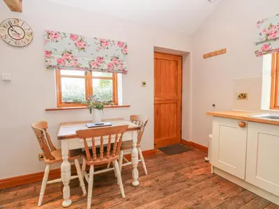 a kitchen with a table and chairs and a window at Maltkiln Cottage At Crook Hall Farm in Mawdesley