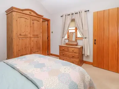 a bedroom with a bed and a dresser and a window at Maltkiln Cottage At Crook Hall Farm in Mawdesley