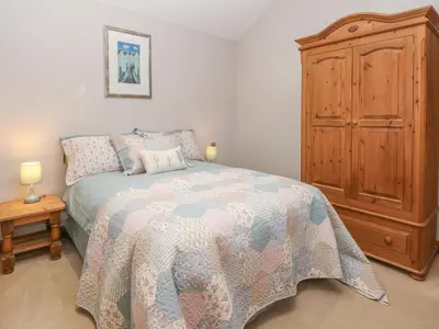a bedroom with a bed and a wooden cabinet at Maltkiln Cottage At Crook Hall Farm in Mawdesley