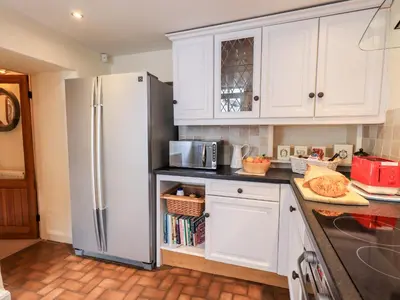 a kitchen with white cabinets and a refrigerator at 4 Greencross Cottages in Holme