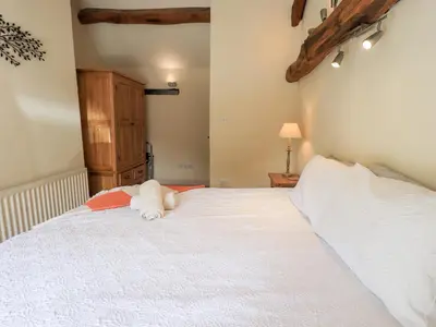a bedroom with a white bed with a stuffed animal on it at 4 Greencross Cottages in Holme