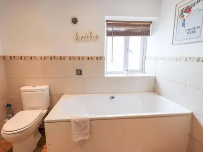 a bathroom with a white tub and a toilet at 4 Greencross Cottages in Holme