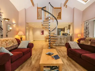 a living room with two couches and a spiral staircase at Eller Riggs Cottage in Ulverston