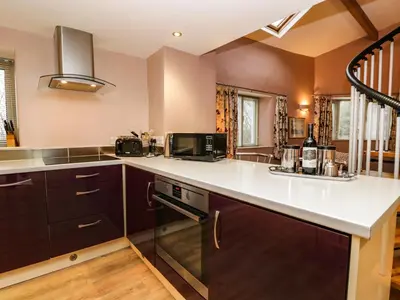 a kitchen with brown cabinets and a white counter top at Eller Riggs Cottage in Ulverston