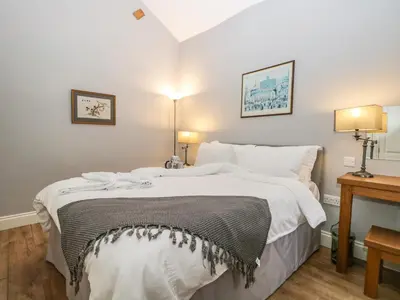 a bedroom with a large white bed with two lamps at Eller Riggs Cottage in Ulverston