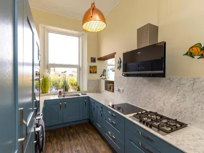 a kitchen with blue cabinets and a sink and a window at Roa Island House in Rampside