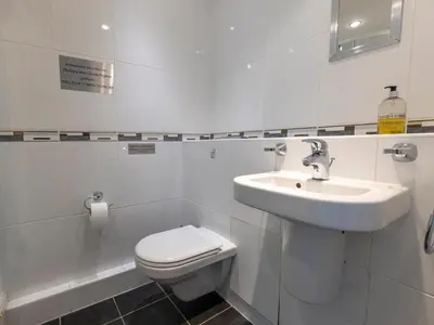 a white bathroom with a toilet and a sink at Roa Island House in Rampside