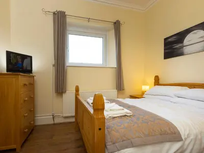 a bedroom with a bed with a dresser and a window at Roa Island House in Rampside