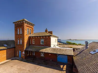 an old brick building with a clock tower on a roof at Roa Island House in Rampside