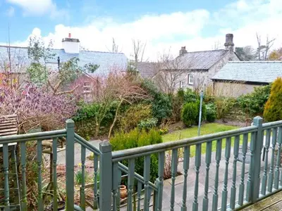 a green fence in front of a yard with houses at The Crook in Great Urswick